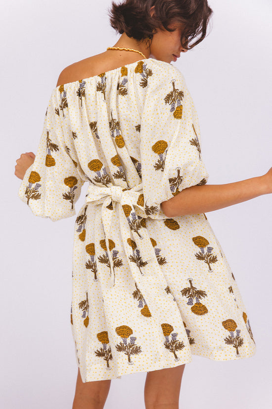 Dahlia Mini Dress Marigold — back view showing tie-waist detail and off-shoulder back neckline, white linen with golden marigold hand block print, billowy sleeve drape, artisan ethical dress | Daughters of India