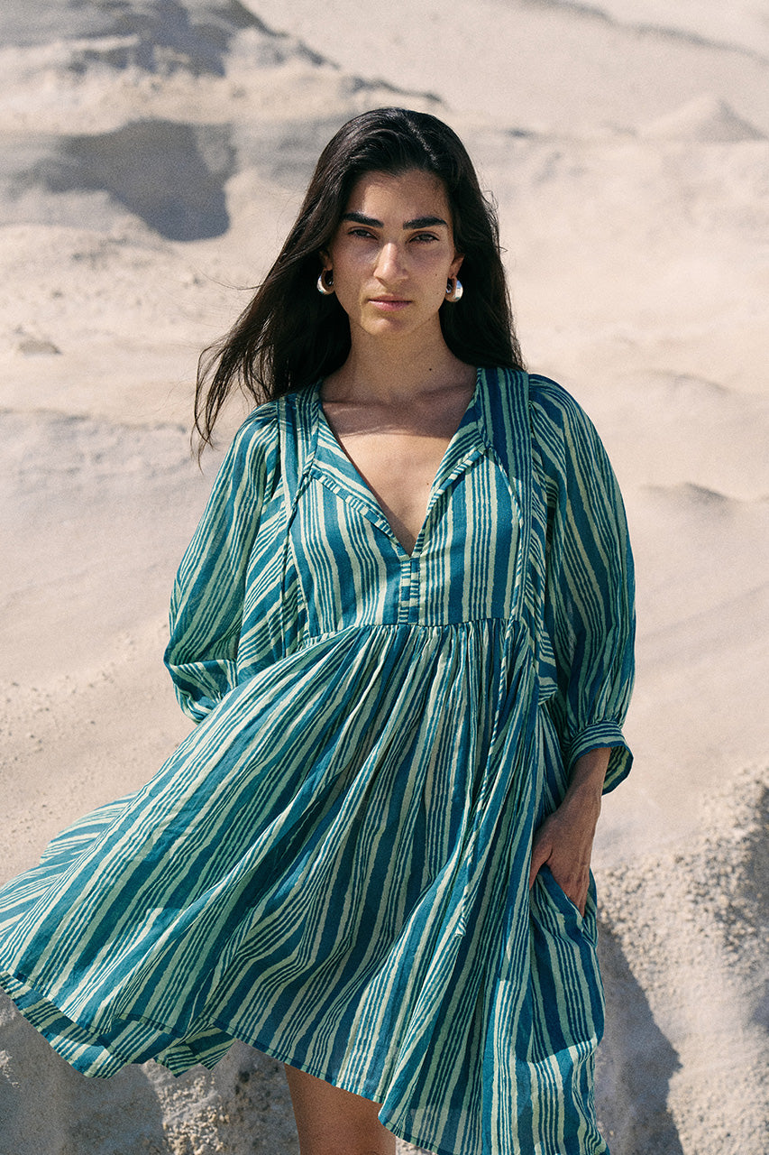 Woman wearing a green and white striped dress on a sandy background